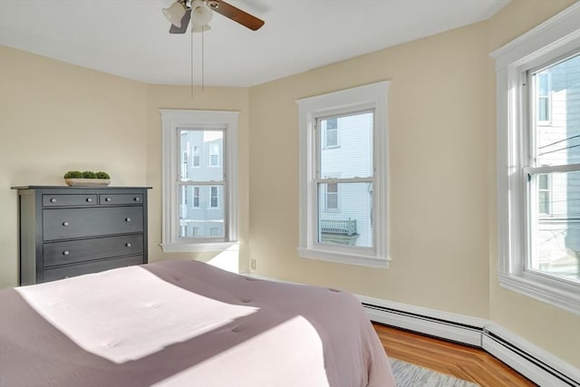 bedroom featuring ceiling fan, light hardwood / wood-style flooring, and a baseboard radiator