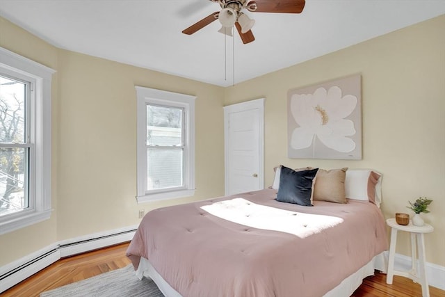 bedroom with multiple windows, ceiling fan, and a baseboard heating unit