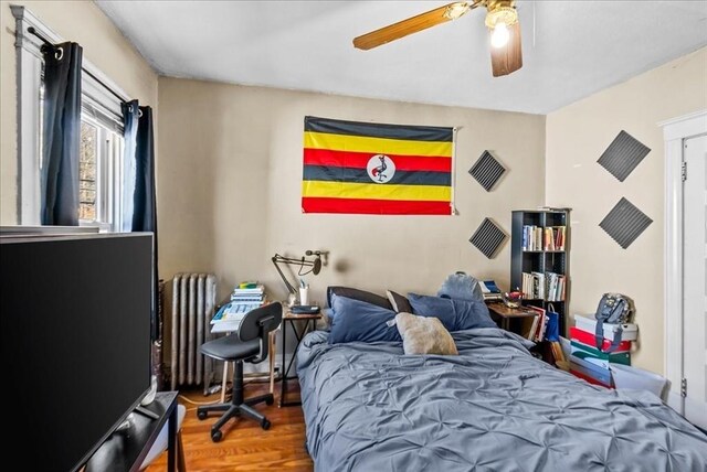 bedroom featuring radiator, a ceiling fan, and wood finished floors