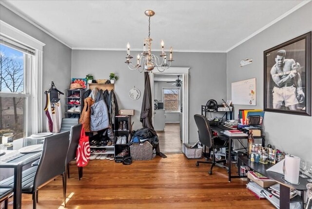 office space with a notable chandelier, wood finished floors, a wealth of natural light, and ornamental molding