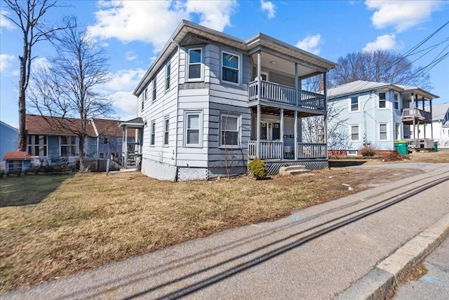 view of front of house with a front yard, a balcony, and covered porch