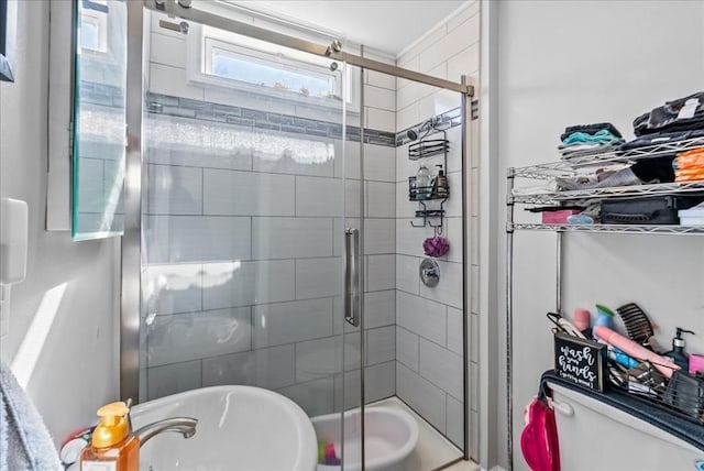 bathroom featuring toilet, a tile shower, and a sink