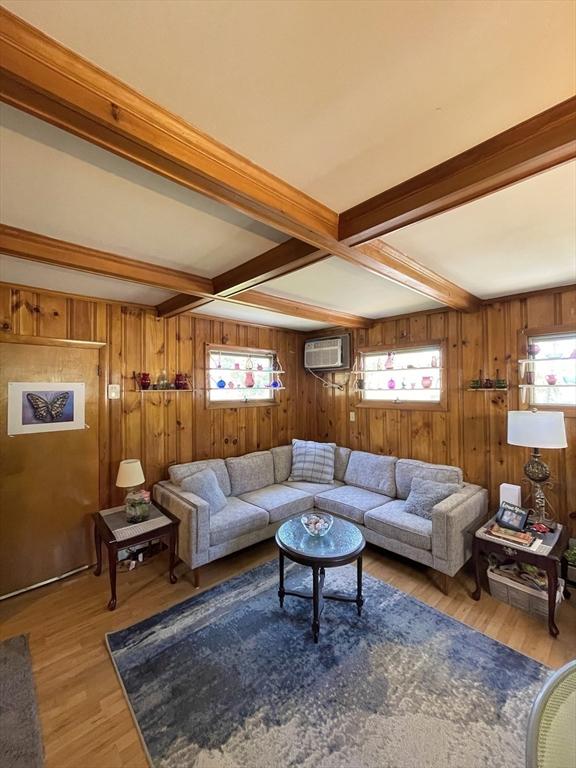 27 Springvale Ave, Lynn, MA 01904 - living area featuring beam ceiling, a wall mounted AC, light wood-style flooring, and wood walls