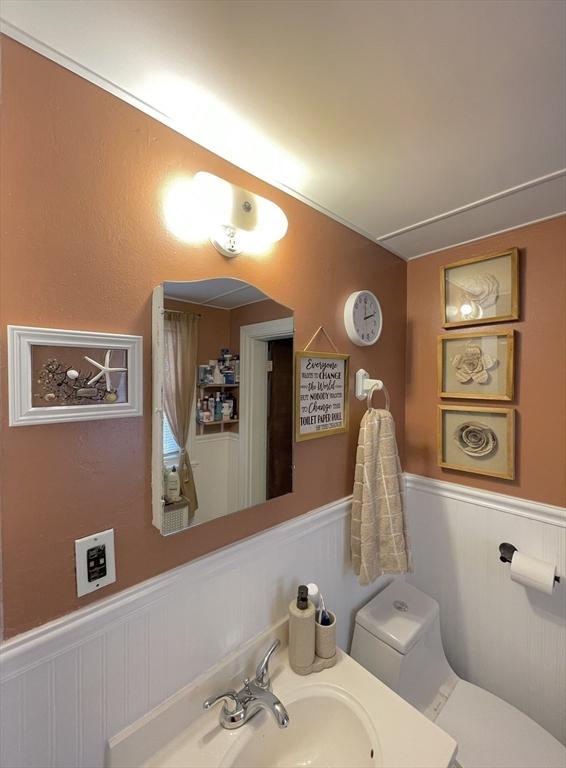 27 Springvale Ave, Lynn, MA 01904 - half bath featuring wainscoting, toilet, a decorative wall, and vanity