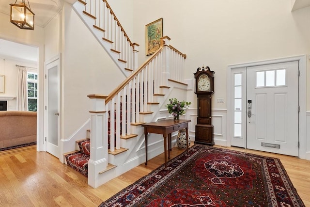 101 Waban St Unit 101, Newton, MA 02458 - foyer featuring wood finished floors, stairs, a high ceiling, and a decorative wall