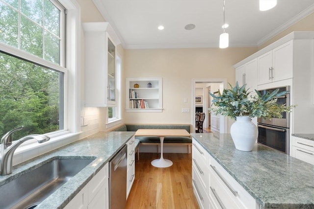 101 Waban St Unit 101, Newton, MA 02458 - kitchen featuring appliances with stainless steel finishes, a sink, ornamental molding, light wood-style floors, and white cabinetry