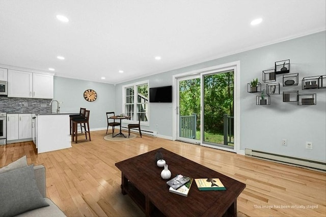 living room featuring baseboard heating, recessed lighting, light wood finished floors, ornamental molding, and baseboards