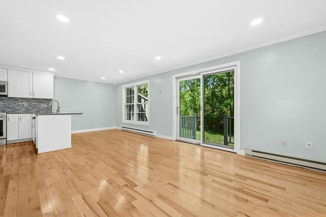 unfurnished living room featuring a baseboard heating unit, crown molding, a sink, light wood-style floors, and recessed lighting
