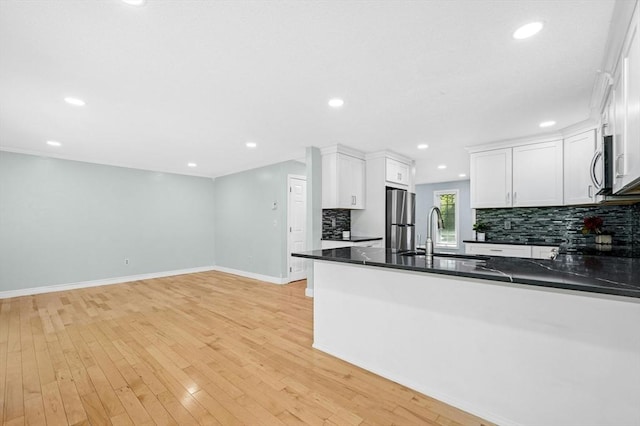 kitchen with a sink, stainless steel appliances, decorative backsplash, dark countertops, and baseboards