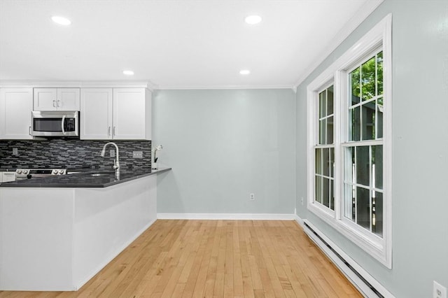 kitchen featuring stainless steel microwave, baseboard heating, a sink, tasteful backsplash, and white cabinetry