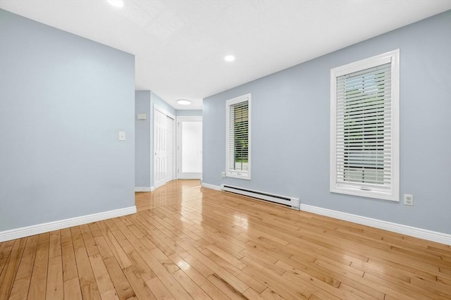 spare room featuring baseboard heating, baseboards, light wood finished floors, and recessed lighting