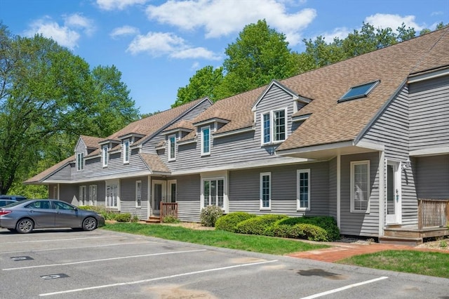 view of front of home with uncovered parking and a shingled roof