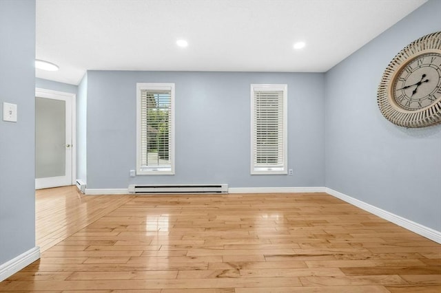 spare room featuring a baseboard heating unit, light wood-style flooring, baseboards, and recessed lighting