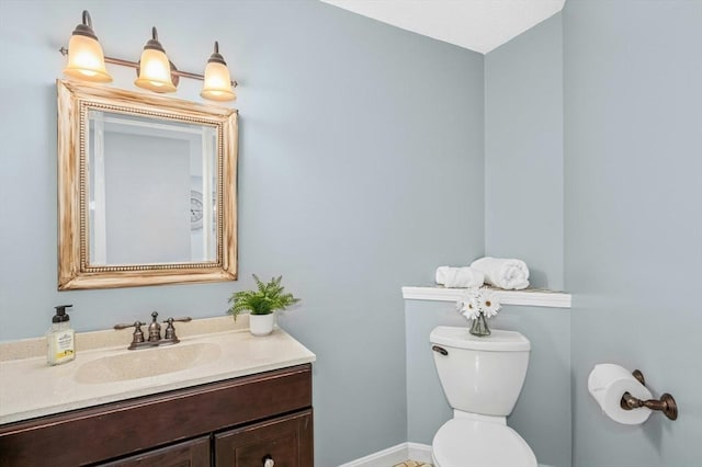 half bath with toilet, vanity, and baseboards