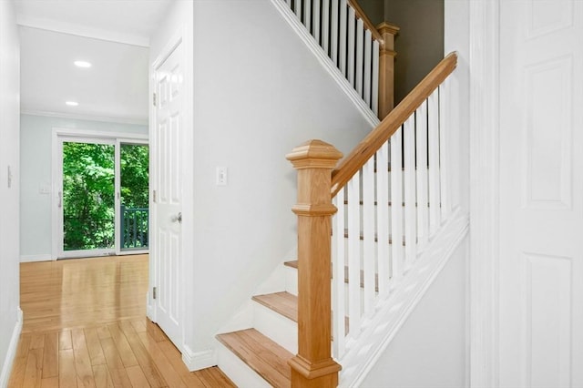 stairway featuring wood finished floors, baseboards, recessed lighting, and ornamental molding