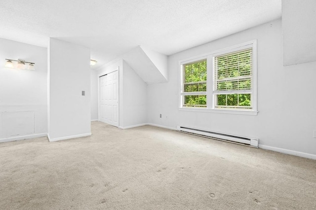 additional living space featuring a baseboard heating unit, carpet floors, baseboards, and a textured ceiling