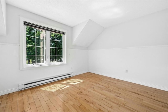 additional living space featuring a baseboard radiator, wood finished floors, vaulted ceiling, and baseboards