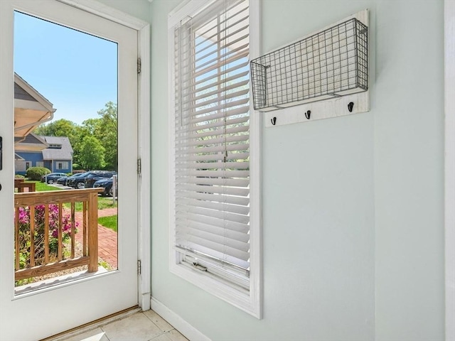 doorway to outside with healthy amount of natural light, tile patterned flooring, and baseboards