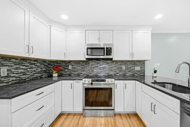 kitchen featuring stainless steel appliances, a sink, decorative backsplash, white cabinets, and crown molding