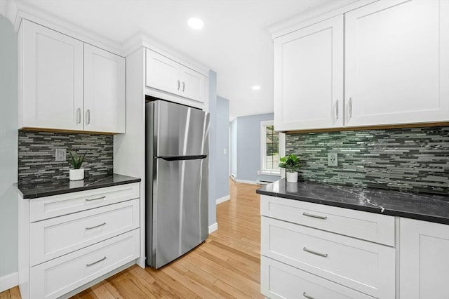 kitchen with freestanding refrigerator, tasteful backsplash, light wood-style flooring, baseboards, and white cabinetry