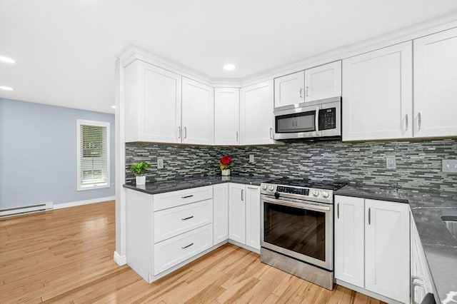 kitchen featuring stainless steel appliances, a baseboard radiator, dark countertops, decorative backsplash, and white cabinetry