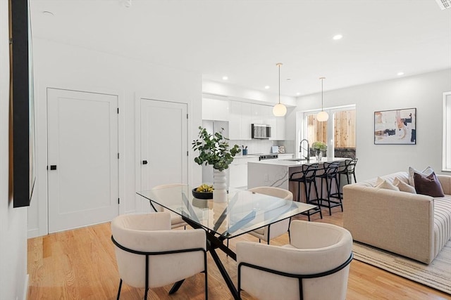 dining space with light wood-type flooring and sink