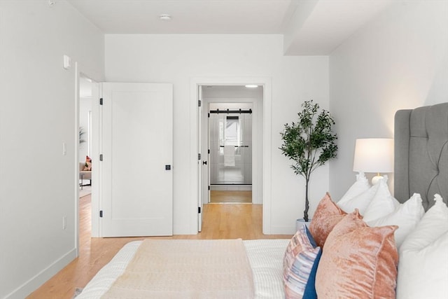 bedroom with light hardwood / wood-style floors and a barn door