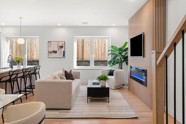 living room featuring sink, light wood-type flooring, and a fireplace