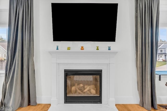 interior details featuring baseboards, a glass covered fireplace, and wood finished floors