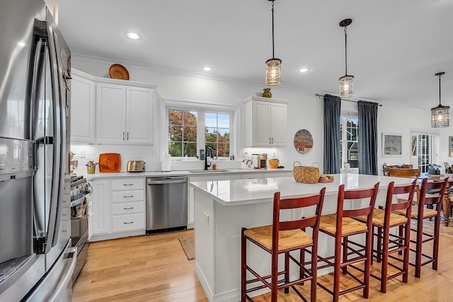 kitchen with light countertops, appliances with stainless steel finishes, a sink, and a center island
