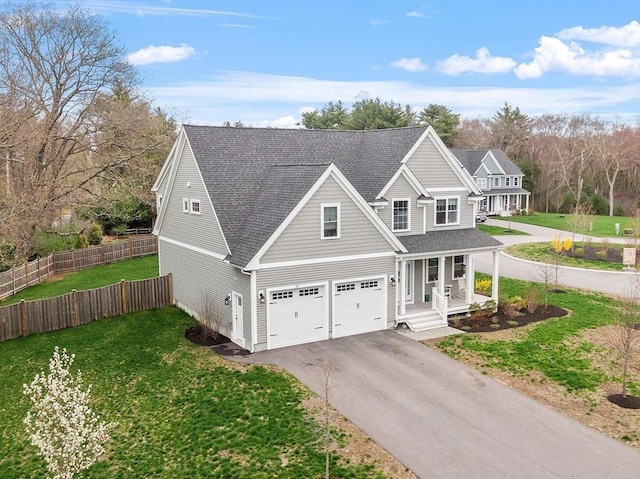traditional-style home featuring fence, an attached garage, a front yard, covered porch, and driveway