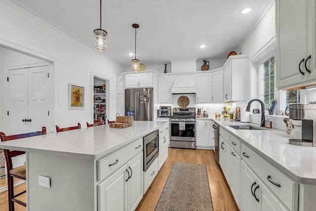 kitchen with stainless steel appliances, a breakfast bar, ornamental molding, and a sink