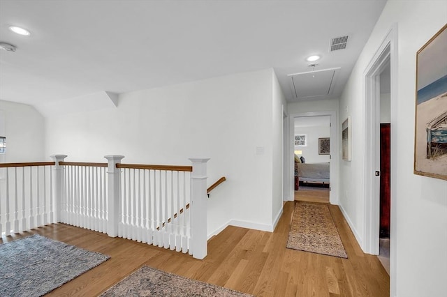 hallway with attic access, visible vents, an upstairs landing, light wood-style floors, and recessed lighting