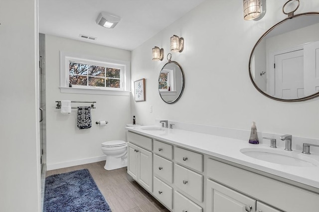 full bath featuring double vanity, toilet, visible vents, and a sink