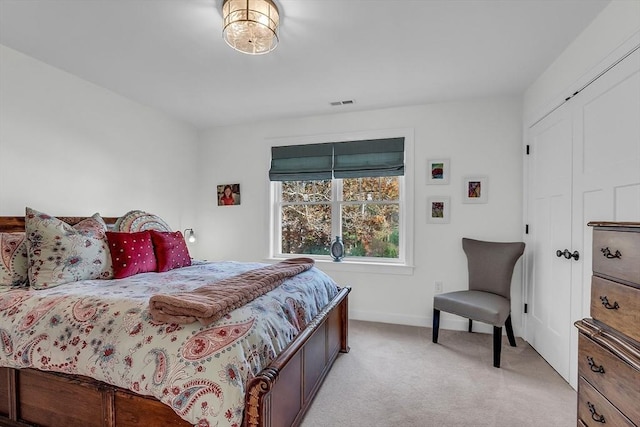 bedroom with baseboards, light colored carpet, visible vents, and a closet