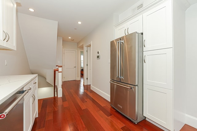 interior space featuring appliances with stainless steel finishes, light stone countertops, white cabinets, and hardwood / wood-style floors