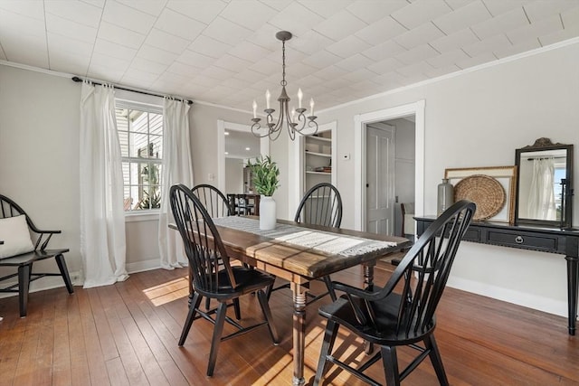 dining room with a notable chandelier, crown molding, and dark wood-type flooring