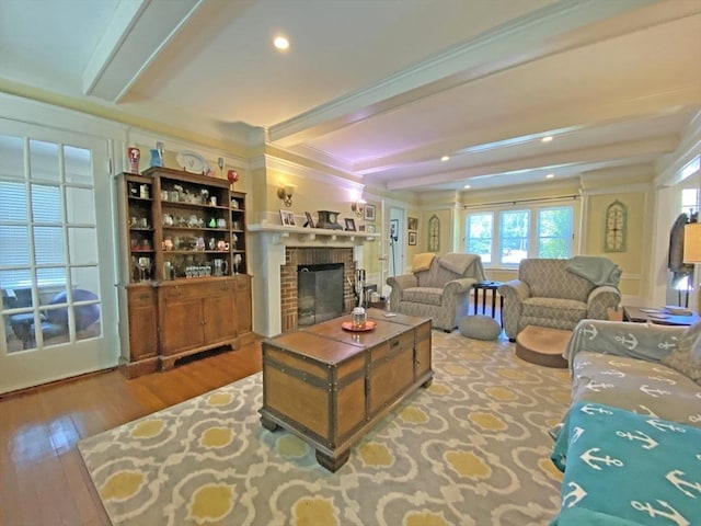 living area featuring beam ceiling, a brick fireplace, wood finished floors, and recessed lighting