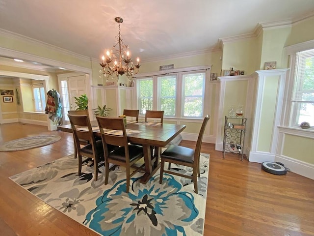 dining room featuring light wood-style floors, a chandelier, baseboards, and ornamental molding