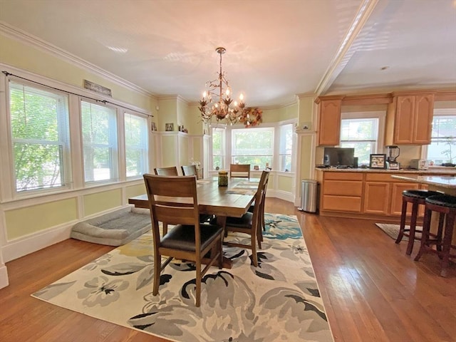 dining room with a chandelier, light wood finished floors, and ornamental molding