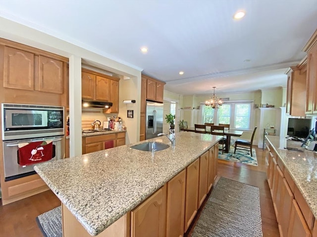 kitchen featuring appliances with stainless steel finishes, a sink, under cabinet range hood, a chandelier, and light stone countertops