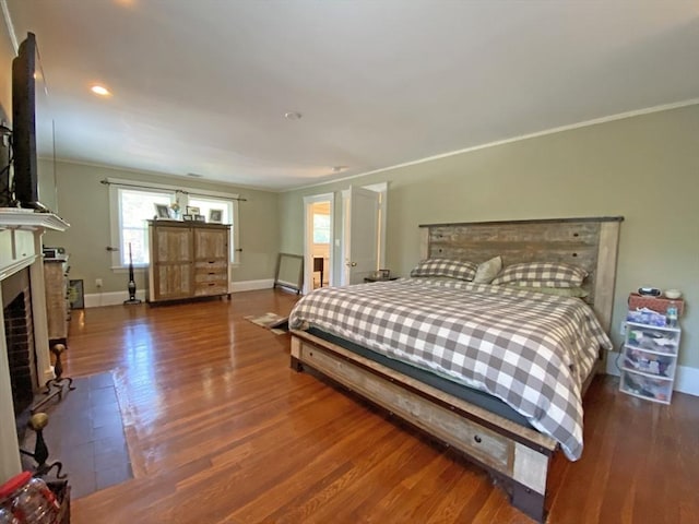 bedroom featuring baseboards, crown molding, wood finished floors, a fireplace, and recessed lighting