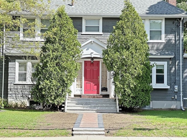 multi unit property with a front lawn, a chimney, and a shingled roof