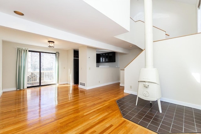 unfurnished living room featuring visible vents, baseboards, and wood finished floors