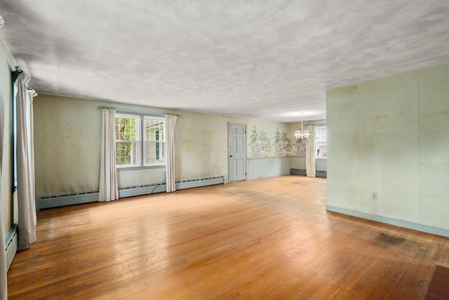 35 Chapin Rd, Holden, MA 01520 - unfurnished living room with a chandelier, wood-type flooring, plenty of natural light, wainscoting, and a baseboard heating unit