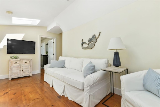 living room with a skylight, hardwood / wood-style flooring, baseboards, and lofted ceiling