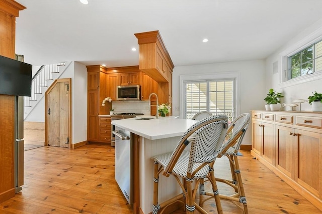 kitchen with stainless steel appliances, a sink, light wood-style floors, light countertops, and recessed lighting