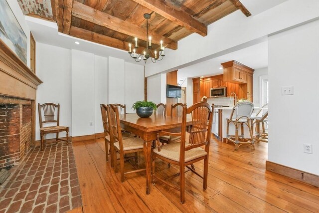 dining area with wooden ceiling, beam ceiling, baseboards, a chandelier, and a fireplace