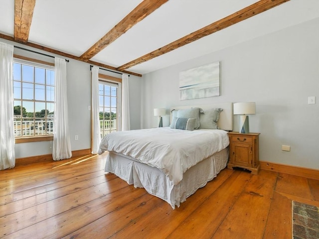 bedroom with access to outside, baseboards, beam ceiling, and light wood-type flooring