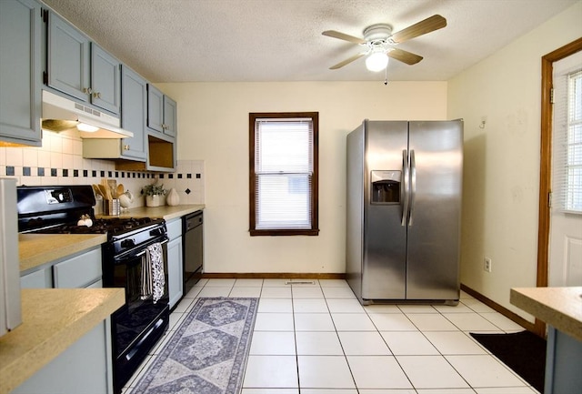 kitchen featuring light tile patterned floors, tasteful backsplash, under cabinet range hood, light countertops, and black appliances